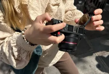 Aparat AgfaPhoto Realishot C130 z odchylonym ekranem w dłoniach fotografującej osoby