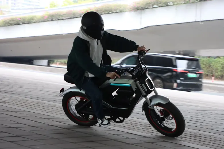 Rowerzysta w kasku jedzie elektrycznym rowerem AOTOS Flux X26 Pro po miejskiej ulicy