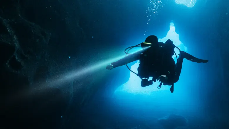 Nurek w masce AREX z latarką Sync Dive Torch w podwodnej jaskini