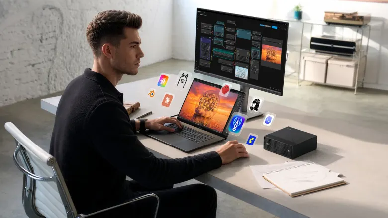Mężczyzna pracujący przy biurku z laptopem ASUS ProArt i mini PC GR1X obok monitora z grafiką