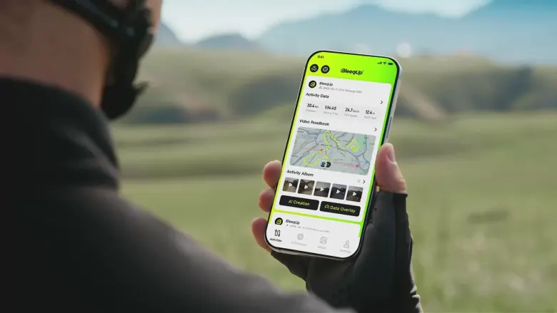 Rowerzysta trzyma telefon z aplikacją BleeqUp i mapą trasy w AI Video Roadbook