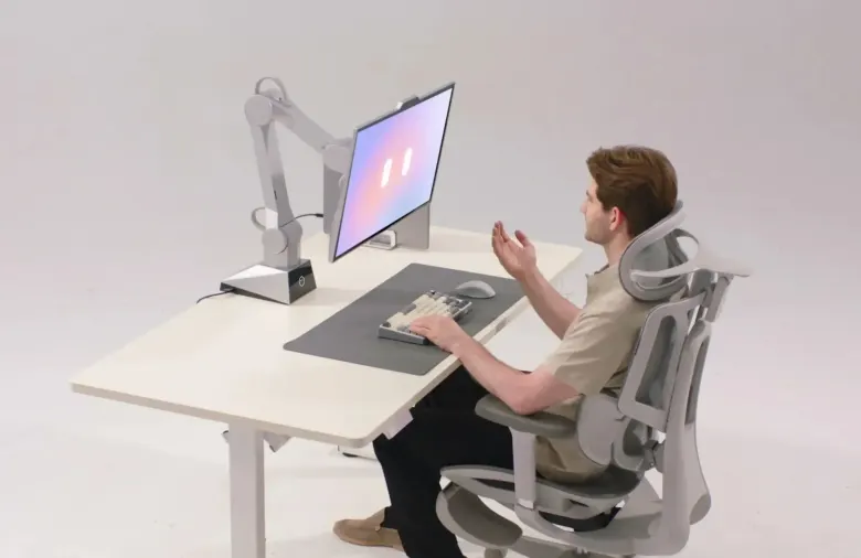 Mężczyzna przy biurku gestykuluje w stronę monitora CyboPal ONE na robotycznym ramieniu