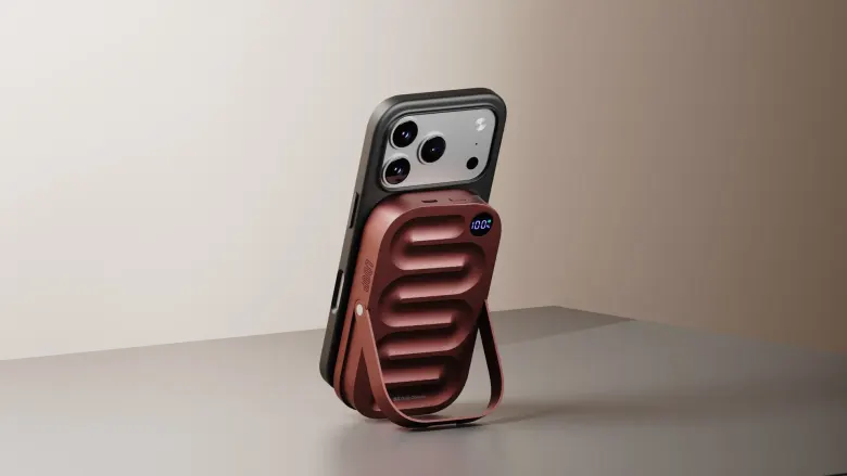 Powerbank DailyObjects Loop Qi2.2 w kolorze Mocha z rozłożoną podstawką, przypięty magnetycznie do iPhone'a