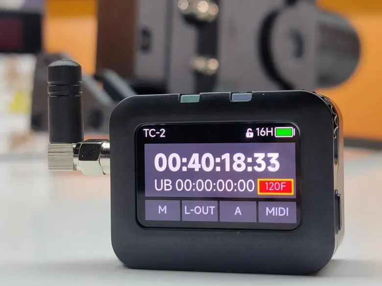 Generator timecode Deity TC-2 z anteną i ekranem AMOLED pokazującym kod czasowy 120 fps