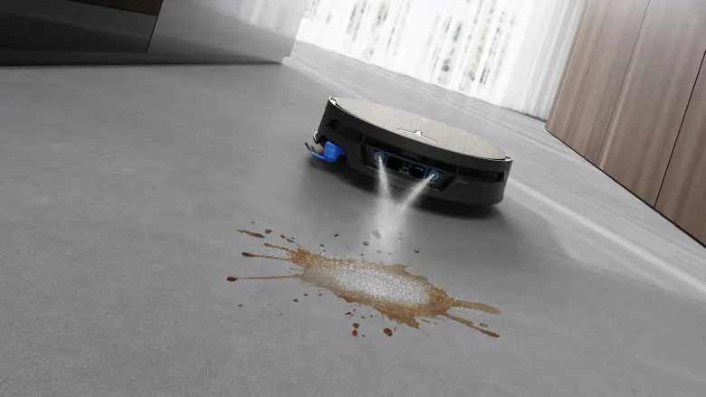 Robot DEEBOT X12S spryskujący zaschniętą plamę kawy na szarej podłodze