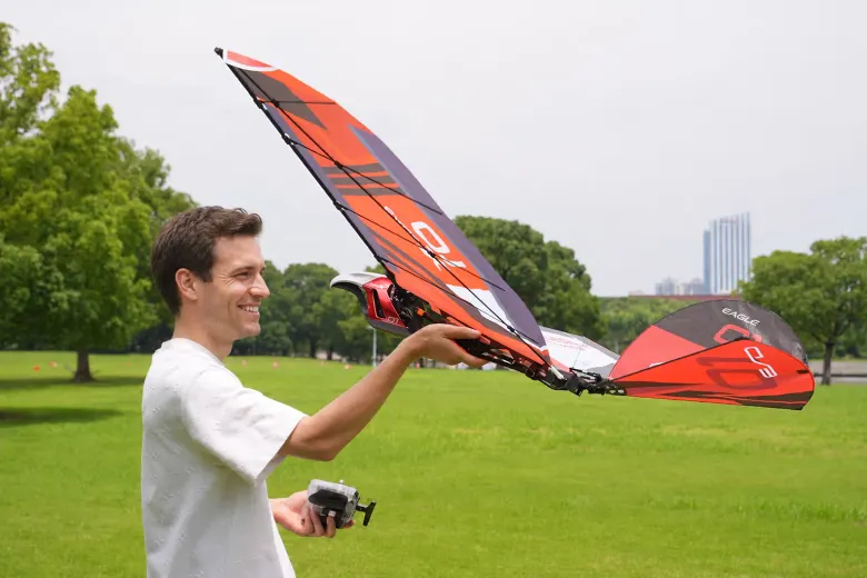 Mężczyzna trzyma ornitopter Eagle X przed startem z ręki, w drugiej dłoni ma aparaturę RC