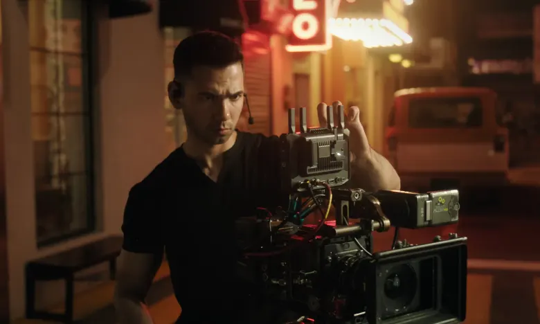 Operator ustawia monitor Hollyland Pyro 7 Ultra zamontowany na kamerze filmowej, nocna ulica w tle