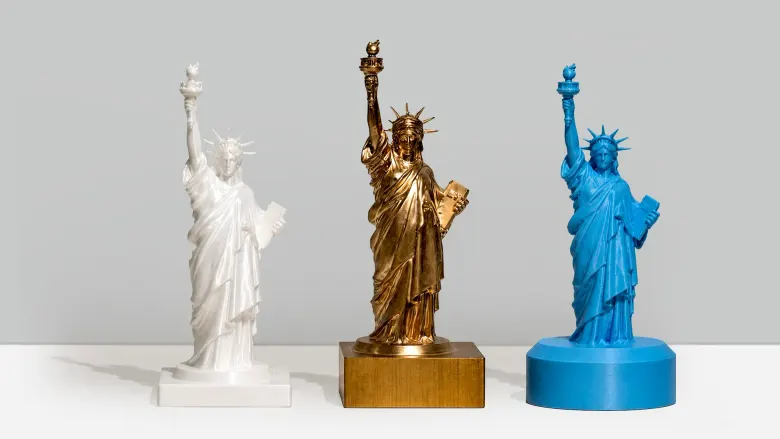 Trzy figurki Statuy Wolności: dwie wydrukowane w 3D z plastiku i jedna wyfrezowana z mosiądzu na InfiMaker K1