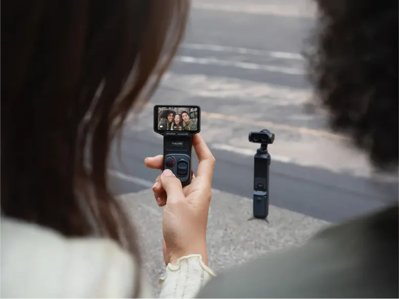 Odłączany ekran Insta360 Luna Ultra w dłoni z podglądem nagrania, kamera z gimbalem stoi w tle