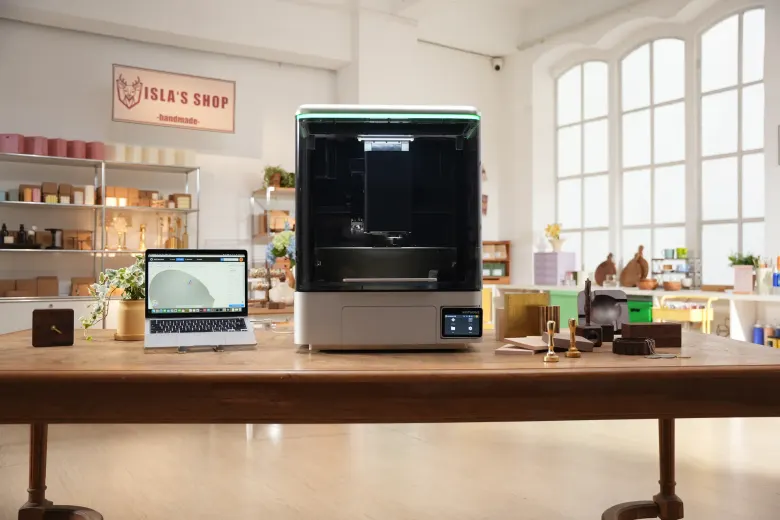 NestWorks C500 na drewnianym stole w rękodzielniczej pracowni, obok laptop z modelem 3D