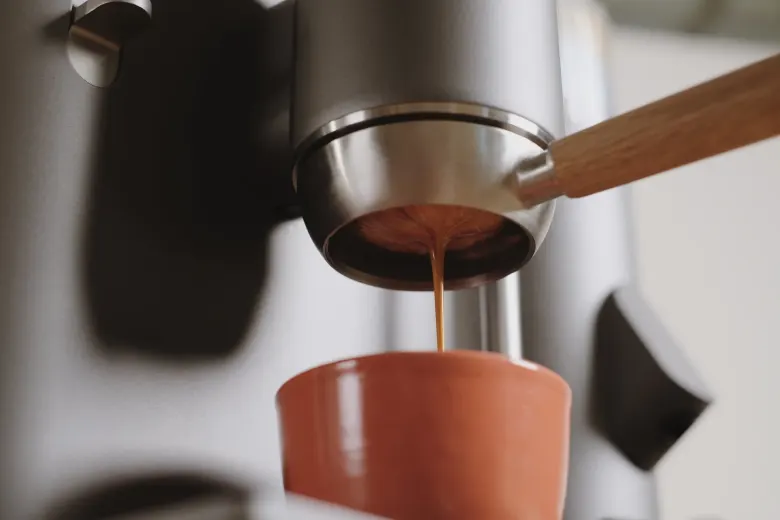 Espresso wypływające z kolby z drewnianą rączką do ceramicznego kubka