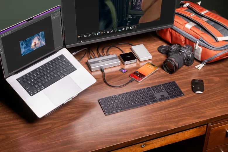 Laptop na biurku podłączony do huba OWC USB4 z dyskami, czytnikiem kart i aparatem obok