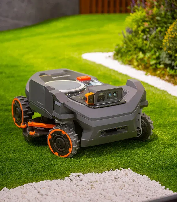 Segway Navimow H5 Pro na trawniku przy rabacie obsypanej białymi kamykami