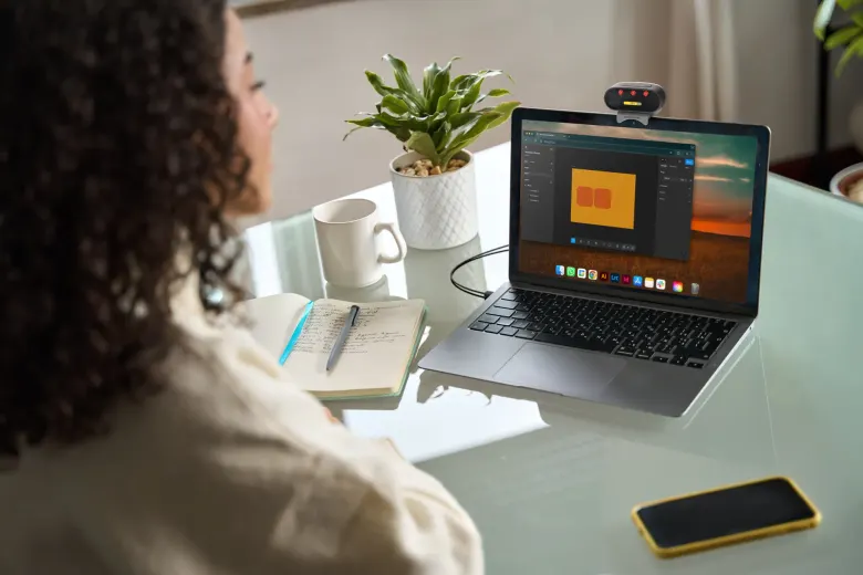 Kobieta pracuje przy laptopie z przypiętą nad ekranem lampą SunBooster