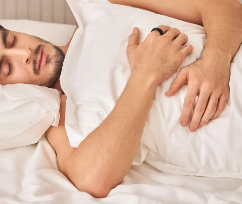 Śpiący mężczyzna z pierścieniem Ultrahuman Ring Air na palcu