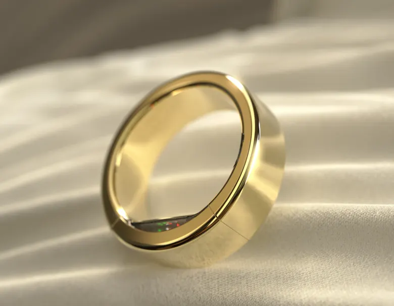 Złoty pierścień Ultrahuman Ring PRO w kolorze Bionic Gold leżący na tkaninie