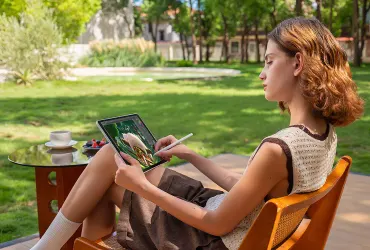Kobieta rysuje rysikiem na tablecie XPPen Magic Pro 13, siedząc w ogrodzie