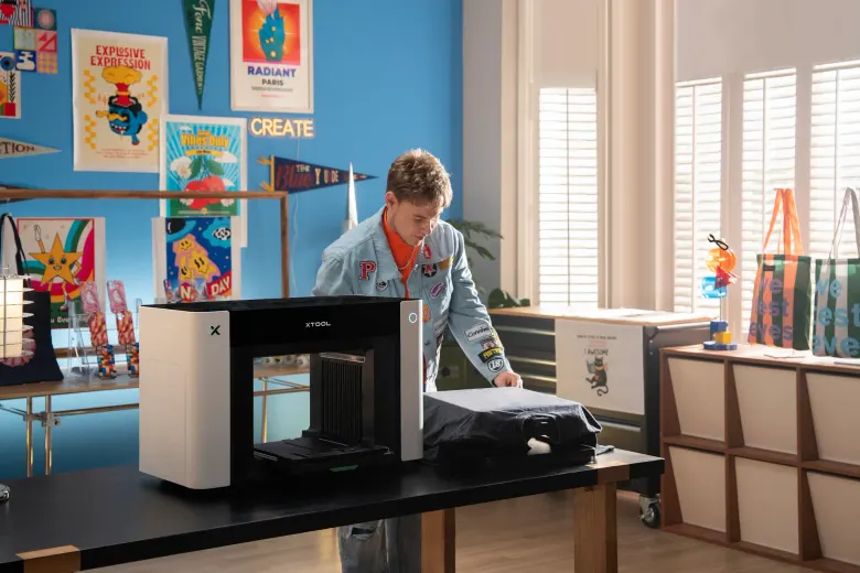 Mężczyzna wkłada koszulkę do drukarki xTool O1 Omni do druku DTG
